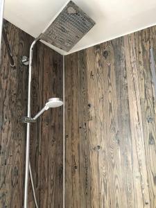 a shower in a bathroom with a wooden wall at Ferienwohnung Wolff am Natursteig Sieg und Westerwald in Pracht