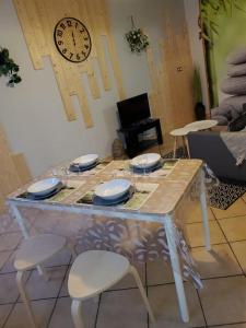una mesa con cuatro sillas y un reloj en la pared en Sélénite, Chaleureuse et Cocooning. en Braux