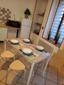 una mesa con sillas y platos en la cocina en Sélénite, Chaleureuse et Cocooning. en Braux