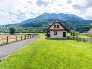 uma pequena casa num campo com montanhas ao fundo em King’s Rock Guesthouse em Zarnesti