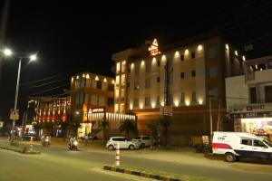 a city street at night with cars parked in front of a building at Hotel Annpurna Regency in Sīkar