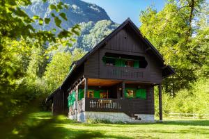 a wooden house with green doors and a mountain at Holiday home Pri Metki - Bohinj in Bohinj