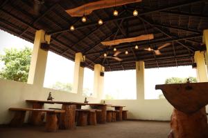 a large room with wooden tables and large windows at Maati Nature Resort in Kankauli