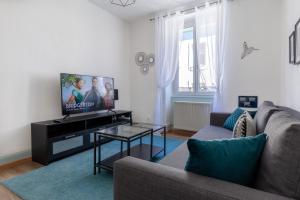 ein Wohnzimmer mit einem Sofa und einem Flachbild-TV in der Unterkunft Travel Homes - Le Carls 1 spacieux, moderne, équipé in Mulhouse