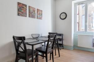einen Esstisch mit Stühlen und eine Uhr an der Wand in der Unterkunft Travel Homes - Le Carls 1 spacieux, moderne, équipé in Mulhouse