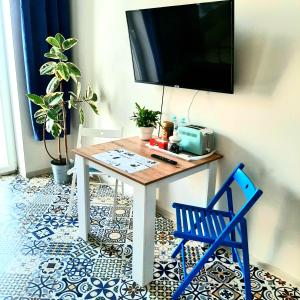 a table with a television and a blue chair at Apartament u Olechny 3 in Bydgoszcz