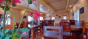 a restaurant with wooden tables and chairs and pink flowers at Vanprastha Resorts in Dwārāhāt