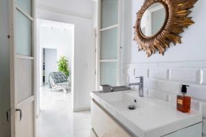 een badkamer met een wastafel en een spiegel aan de muur bij El Erizo Apartamentos in Tarifa