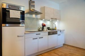 a kitchen with white cabinets and a sink at Alpok-Spirit Apartment – Velem in Velem