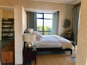 a bedroom with a bed and a large window at Vetho Farmhouse Dullstroom in Dullstroom