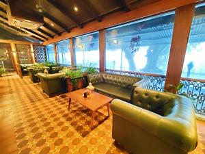 un vestíbulo con sofás y una mesa en una habitación en Regenta MPG Club Mahabaleshwar, en Mahabaleshwar