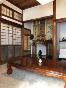 sala de estar con mesa de madera y algunas ventanas en 島宿糸 en Iki