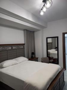 a bedroom with a large white bed and a mirror at Brickell Hotel apto g 08 Santo Domingo Bella Vista in Santo Domingo