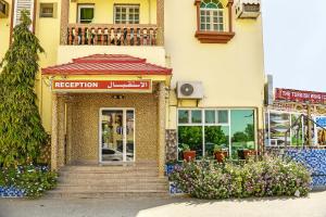 una fachada de un edificio con una puerta y flores en OYO 140 Al Musafir Hotel, en Barka