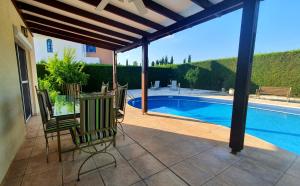 un patio con sedie e una piscina di Villa Victoria 400 meters to the beach a Peyia