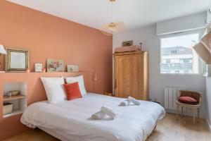 a bedroom with a large white bed with orange walls at Appartement proche centre ville et face a l Erdre in Nantes