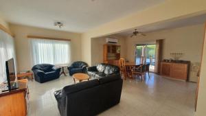 un soggiorno con un divano, sedie e un tavolo di Villa Victoria 400 meters to the beach a Peyia