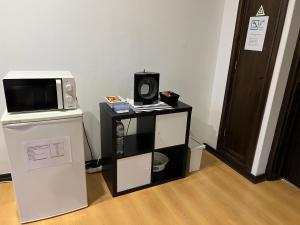 a small black and white microwave and a refrigerator at Espaço_Zero[Downtown] 01 in Porto