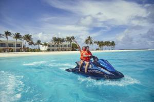 a man and a woman riding a jet ski in the water at Riu Palace Maldivas- All Inclusive in Dhaalu Atoll