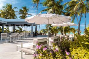 eine Terrasse mit Liegestühlen und Sonnenschirmen am Strand in der Unterkunft Riu Palace Maldivas- All Inclusive in Dhaalu Atoll