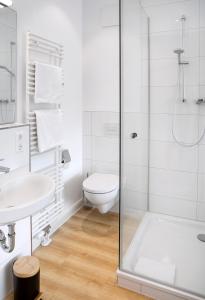 uma casa de banho branca com um chuveiro e um WC. em Louis & Louise Apartments & Rooms I Digital Check In em Bremen