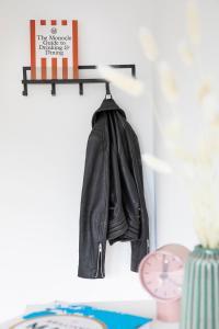 une veste noire en cuir suspendue sur une étagère dans l'établissement Louis & Louise Apartments & Rooms I Digital Check In, à Brême