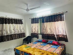a bedroom with a bed and two windows with curtains at RJ Villa farmhouse in Daman