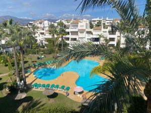 een luchtzicht op een zwembad van het resort met palmbomen bij Precioso apartamento a pie de playa in Estepona