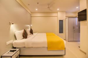 a bedroom with a bed with a yellow blanket at Housemate Hotel in Pune