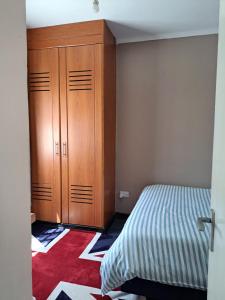 1 dormitorio con 1 cama y armario de madera en Kwinet Luxury Villa, en Eldoret