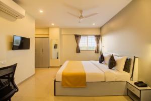 una camera con un grande letto e una televisione di Housemate Hotel a Pune