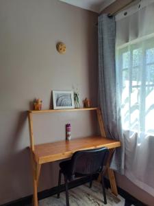 einen Holzschreibtisch mit einem Stuhl neben einem Fenster in der Unterkunft Kwinet Luxury Villa in Eldoret
