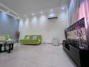 a living room with a tv and a green couch at Sasna in Doha