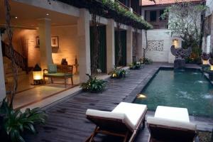 a swimming pool in a house with chairs and a table at Cinta inn in Ubud