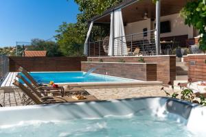 ein Pool mit zwei Gartenstühlen und ein Haus in der Unterkunft Villa Little Arya in Otok