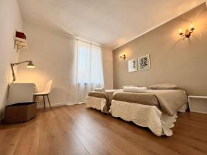 a bedroom with two beds and a desk and a window at Ottanio Lake Apartment in Pisogne