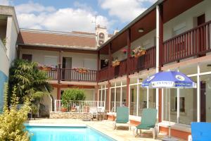 un hotel con piscina, sombrilla y sillas en Logis Hotel au tambour en Reims