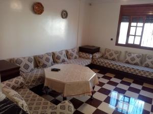 a living room with couches and a table and a window at Grand appartement proche de la plage in Agadir