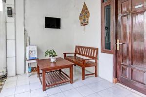 um quarto com um banco, uma mesa e uma cadeira em OYO 91803 Gita Graha Guest House Syariah em Yogyakarta