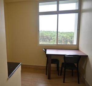uma sala de jantar com uma mesa e 2 cadeiras e uma janela em TreeTops Residency em Shillong