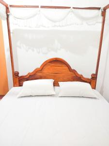 a bed with a wooden headboard and two pillows at Sheen Holiday Resort in Tangalle