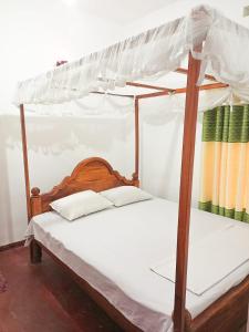 a bedroom with a four poster bed with white sheets at Sheen Holiday Resort in Tangalle