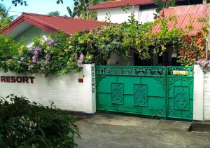 a green gate in front of a house with flowers at Sheen Holiday Resort in Tangalle