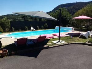 Coubon的住宿－Gîte "Le temps d'une pause" terrasse et piscine，一个带两把椅子和遮阳伞的游泳池