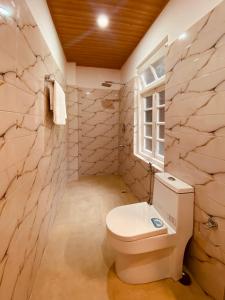 a bathroom with a white toilet and a window at THE APARTMENT in Gangtok