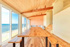 comedor con mesa de madera y ventanas grandes en 日本海夕日ヴィラOne Story 