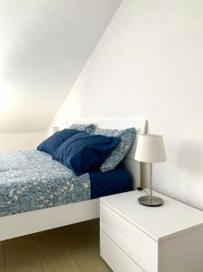 a white bedroom with a bed with blue sheets and a lamp at APPARTAMENTO SFERISTERIO in Macerata