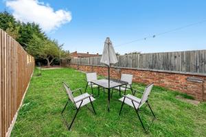 a table and chairs with an umbrella in a yard at Central House with Parking, Pool Table, Super-Fast Wifi and Smart TV with Virgin TV and Netflix by Yoko Property in Northampton