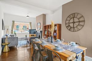 a dining room with a table and a clock on the wall at Central House with Parking, Pool Table, Super-Fast Wifi and Smart TV with Virgin TV and Netflix by Yoko Property in Northampton