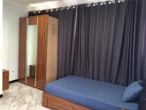 1 dormitorio con cama azul y cortina en Bening Asri Guesthouse, en Gombolpaya